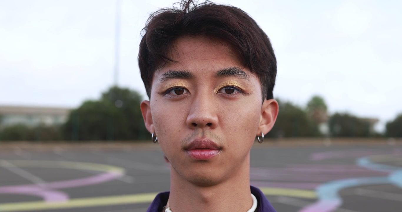 ゴールドのアイシャドウを施した若いアジア人男性のクローズアップポートレート