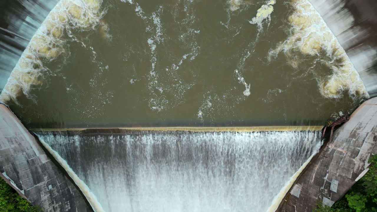 Ascending shot of Presa El Carrizo as water flows over its curved spillway, Mexico. Reveal shot, aerial