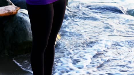 woman performing yoga on the beach
