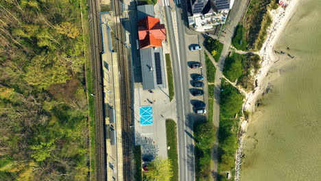 Vista-Aérea-De-Una-Estación-De-Ferrocarril-En-Kuźnica,-Que-Muestra-La-Yuxtaposición-De-Vías-De-Tren,-Carreteras-Y-El-Mar-Adyacente,-Que-Resume-La-Infraestructura-única-De-Esta-Zona-Costera---Vista-Aérea