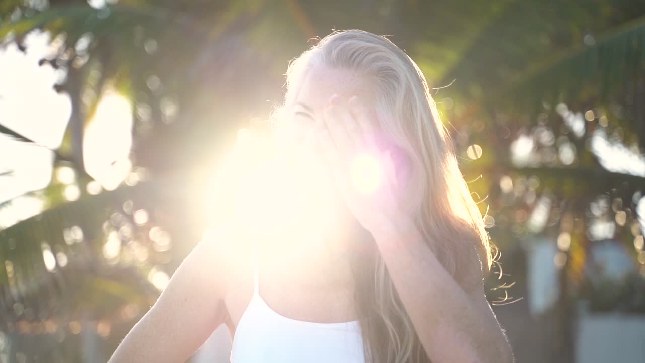 With a sneaky look a mature woman looks at camera, throws her head to side with hair and smiles at camera
