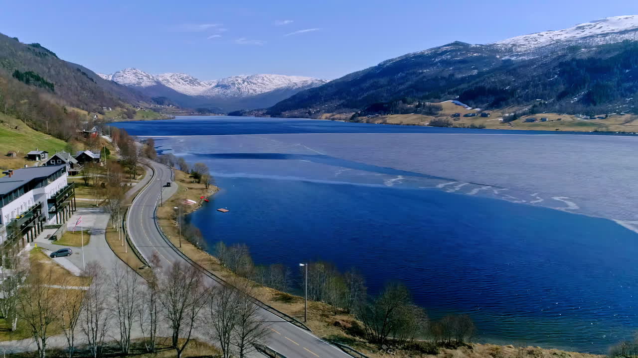 ciudad costera, lago azul y montañas cubiertas de nieve, vista aérea de drones