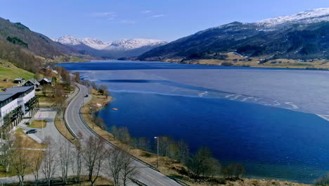 Coastal-town,-blue-lake-and-snowy-capped-mountains,aerial-drone-view