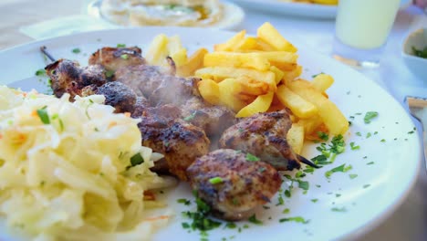 cinemagraph de humo emitido por un shashlik caliente a la parrilla con papas fritas en un plato blanco
