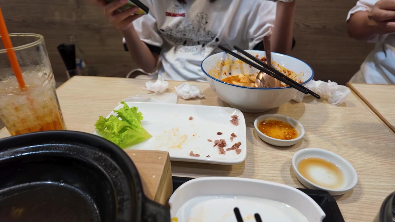 Uma foto de ângulo alto de sopa de macarrão com carne picante e condimentos em uma mesa de restaurante