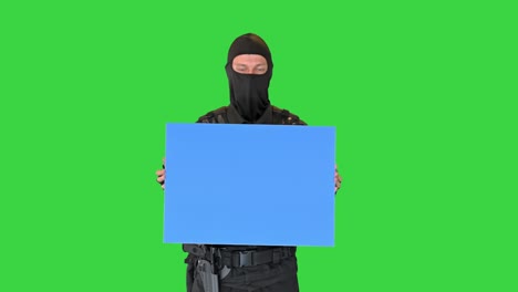 riot policeman holding a blank board on a green screen, chroma key
