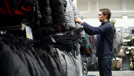 hombre comprando chaquetas en una tienda de ropa