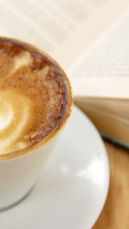 primer plano de una taza de café con un libro abierto