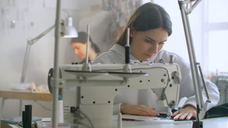 tailoring of clothes. seamstresses at work in workshop sewing clothes on sewing machine. dressmakers sews clothes in atelier. two women seamstress. dressmaking in sewing business.