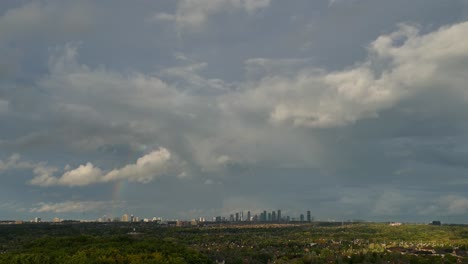 fluffy clouds with rainbow after rain with skyline in the distance