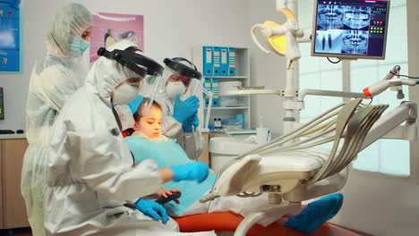 dental technician in protective equipment lighting the lamp for examining child