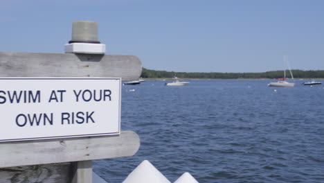 swim at your own risk sign on a dock at the lake in cape cod