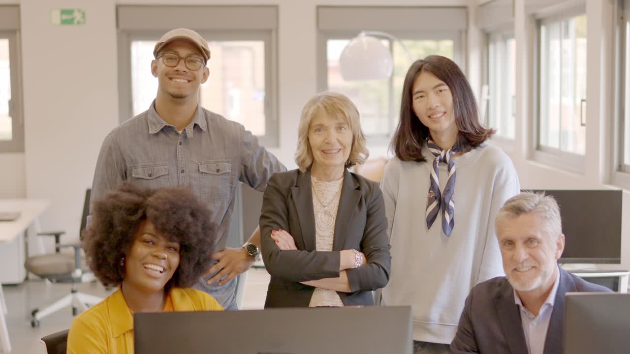 Coworking team smiling at camera standing and sitting together