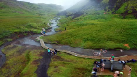 aerial flight over reykjadalur valley steamy mountain river with people relaxing in the hot water - south iceland