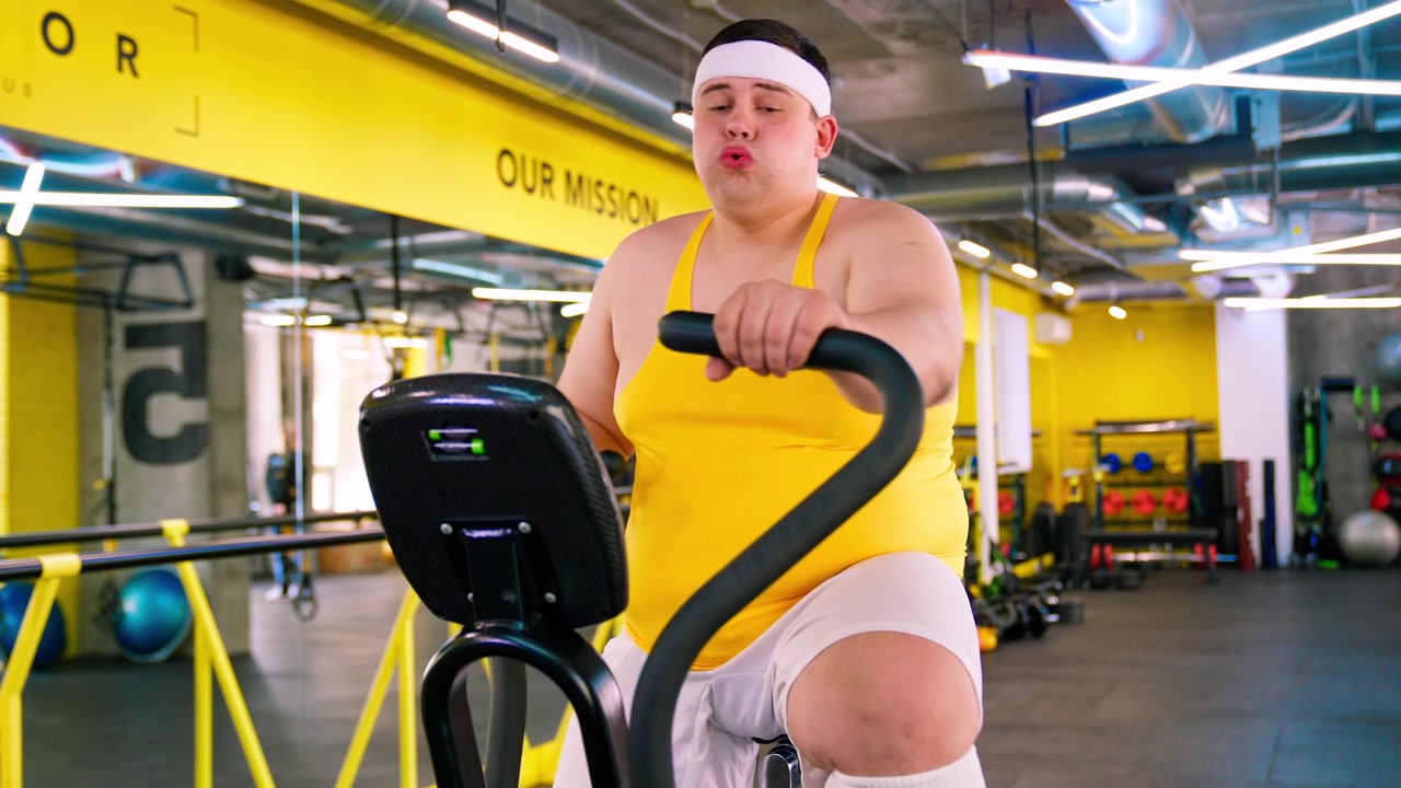 Uomo in sovrappeso che fatica ad allenarsi su un'ellittica in palestra