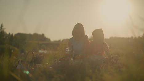 mother and daughter enjoying peaceful outdoor picnic under golden sunlight, sharing snacks and fruit, picnic setup includes water pitcher, snacks, and fruit arranged on picnic mat