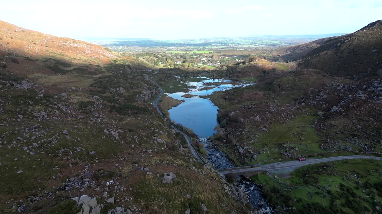 Wide revealing aerial shot of Gap of Dunloe, Bearna or Choim&iacute;n, mountain pass in County Kerry, Ireland, that separates the MacGillycuddy's Reeks mountain range and the Purple Mountain Group