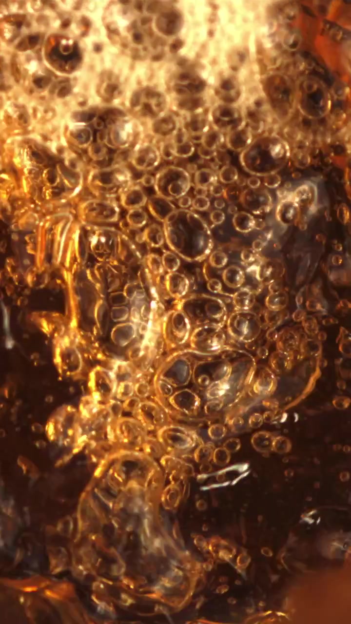 Toma macro de burbujas doradas efervesciendo en una bebida carbonatada