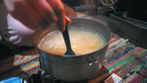 cocinar pasta con una estufa de gas portátil en una cabaña en la naturaleza, al aire libre, acampar