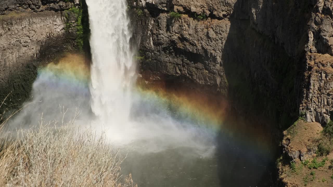 brillantes formas de arco iris en la niebla de la cascada en el fondo del cañón rocoso