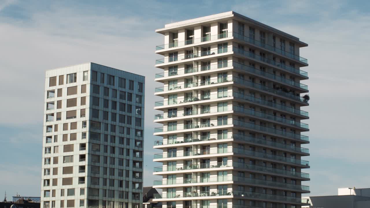 Walking shot of two modern apartment towers in Eilandje, Antwerp showing glass facades and balconies