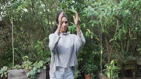 focused biracial woman practicing yoga in sunny garden, slow motion