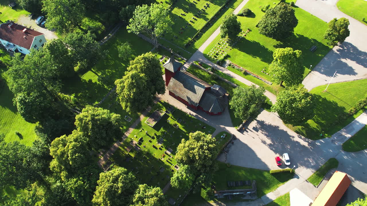A quiet swedish cemetery surrounded by trees and a small church in skållerud, aerial view