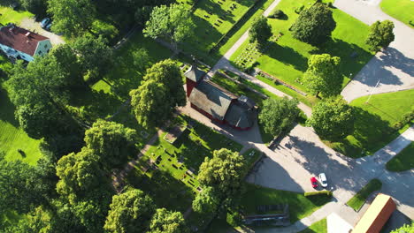 a quiet swedish cemetery surrounded by trees and a small church in skållerud, aerial view