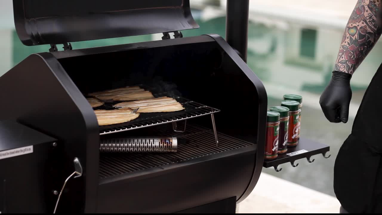 Mann legt geräucherten Fisch vom Grill auf das Schneidebrett