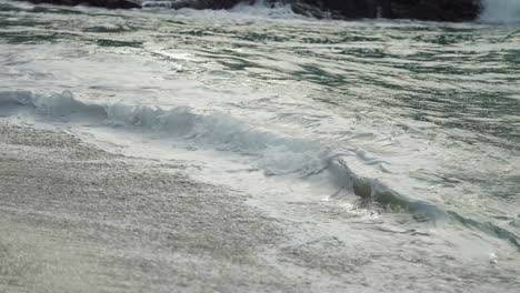 Eine-Nahaufnahme-Der-Langen-Wellen,-Die-Auf-Den-Sandstrand-Schwappen