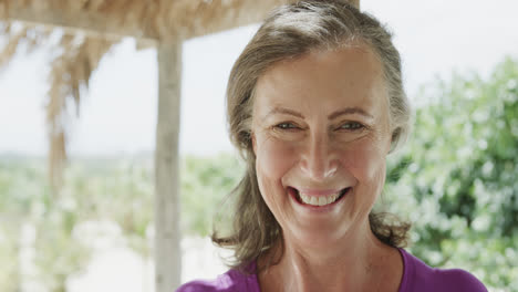 Portrait-of-happy-senior-caucasian-woman-smiling-on-beach,-in-slow-motion