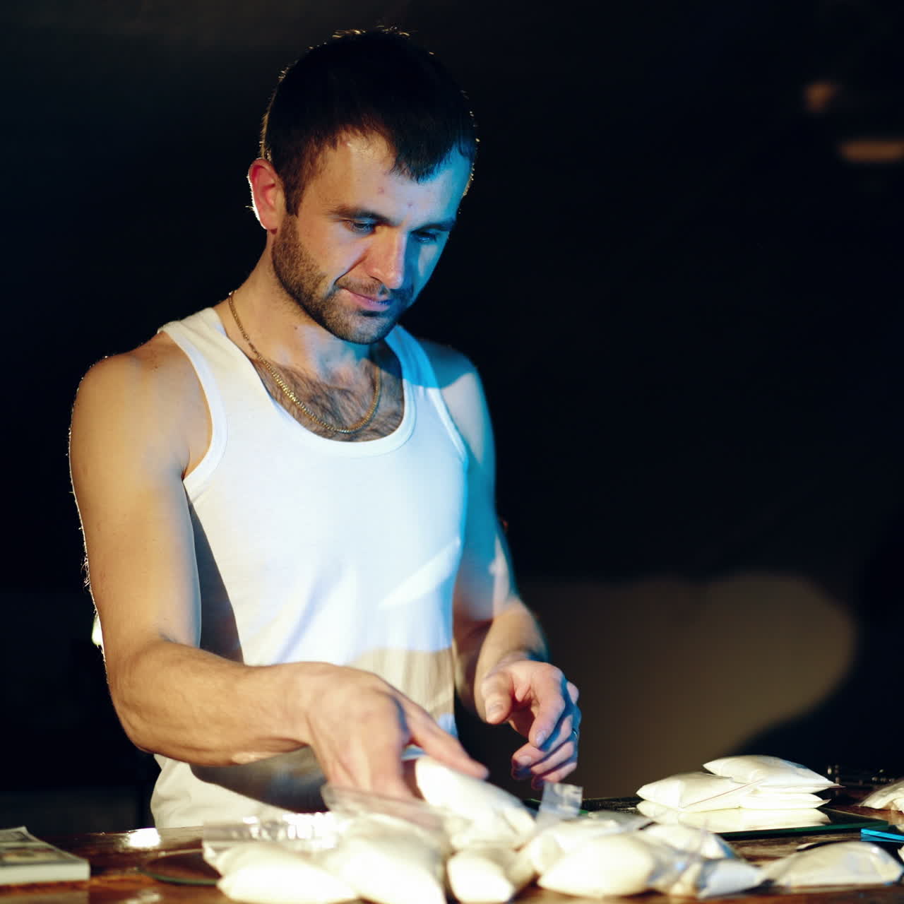 Drugs. In the underground laboratory drug dealer places brick packs filled with drugs Into the suitcase for further selling and distribution. Square video