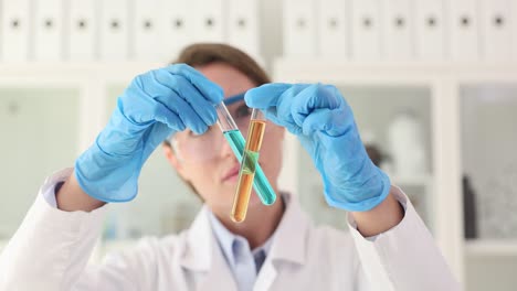 scientist holding two test tubes with colored liquids