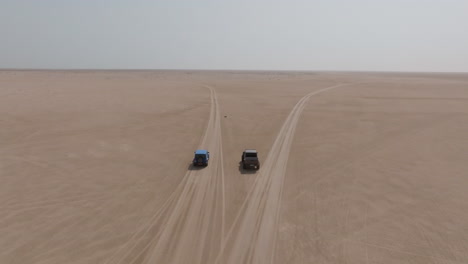 two off-road vehicles driving in the desert towards bar al hikman, oman