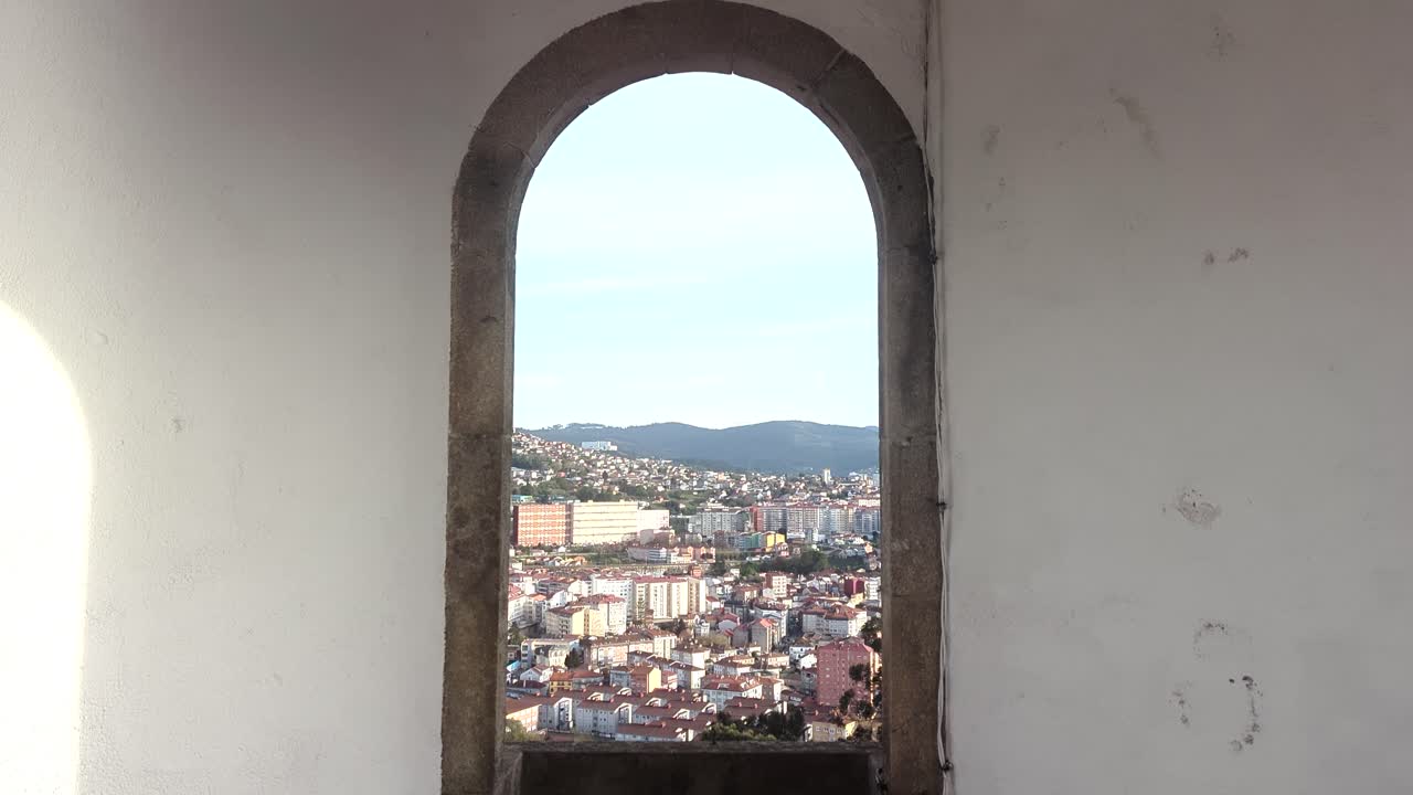 Through an oval window in Vigo, Spain: A scenic vista unfolds over the Galician city, its tranquil Ría (estuary), bustling marina, and surrounding landscape.