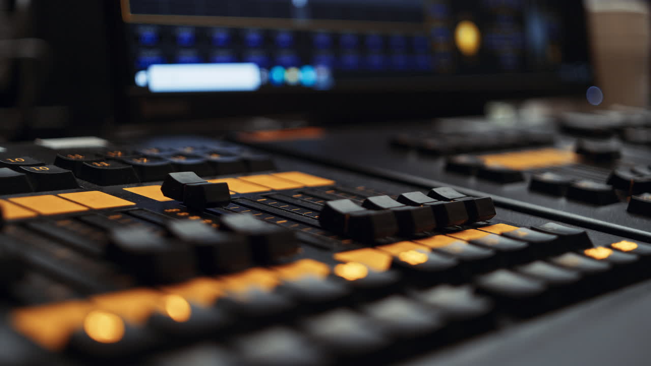 Two center faders of a professional dmx lighting control desk console panel being turned up, making lights brighter