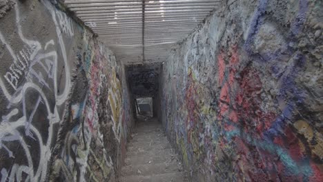 a frightening and dirty corridor leading down the stairs, with graffiti walls and bars on the ceiling