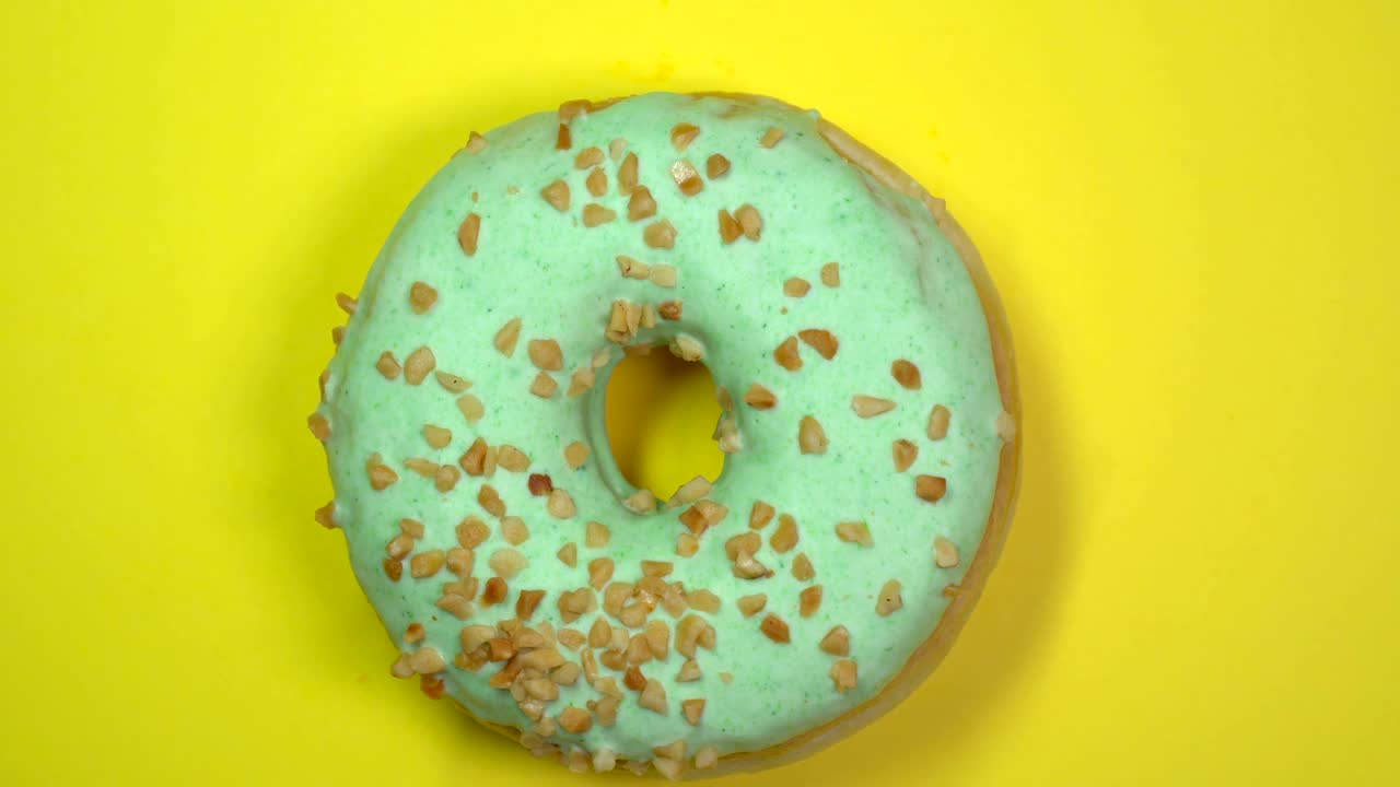 una deliciosa rosquilla verde dulce girando en un plato. vista de arriba.