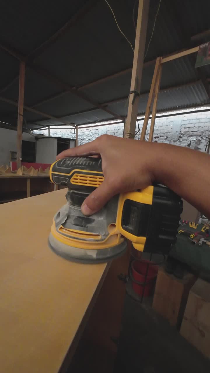 Close-Up of Hand Sanding Wood with an Orbital Sander in a Workshop
