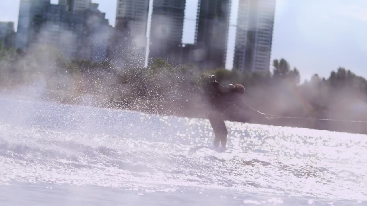 남자가 여름 강에서 빠른 속도로 웨이크 보드를 타고 있다. 익스트림 스포츠