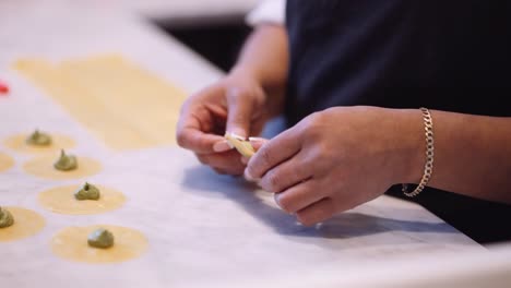 Female-chef-making-tortellini-in-kitchen,-tight