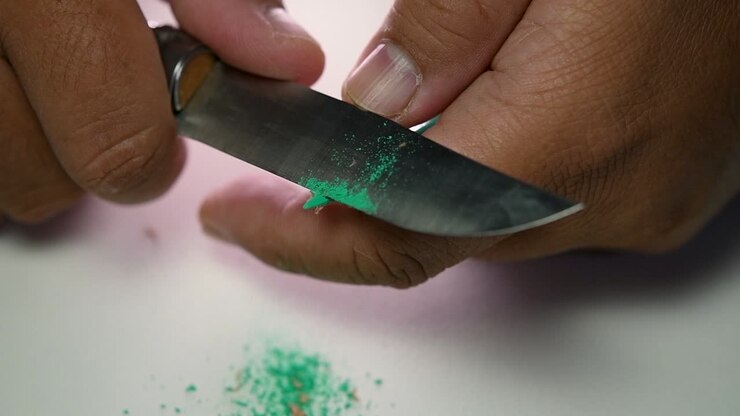 Footage of hands slowly sharpening a pencil and some coloured pencils with a sharp knife