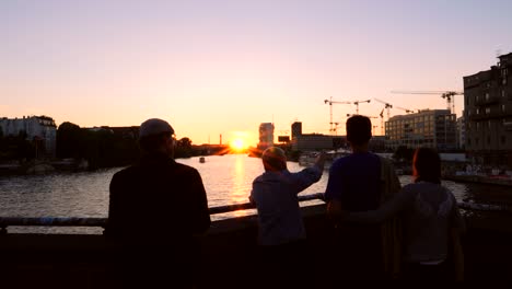 people overlooking river spree at sunset