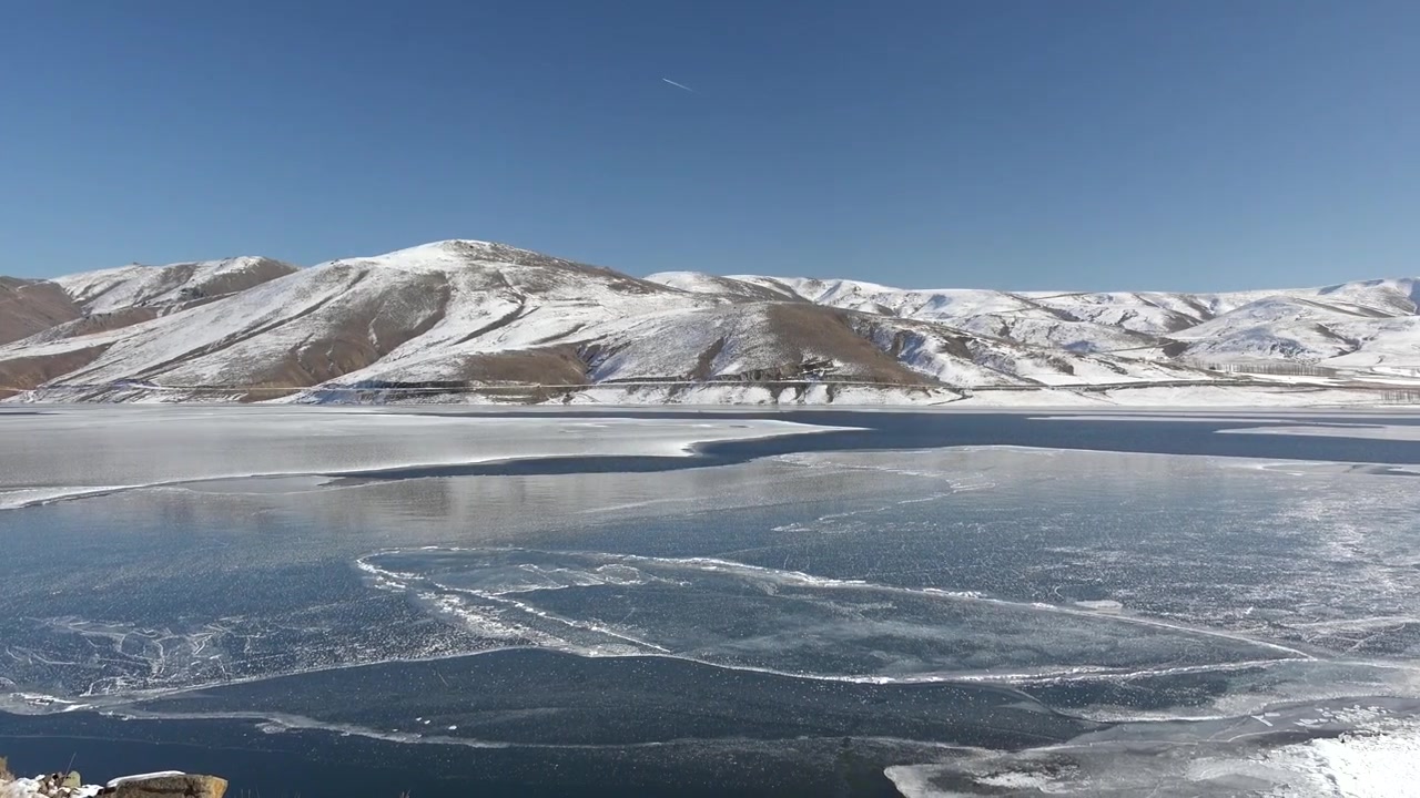 Panoramaudsigt over en frossen sø omgivet af sneklædte bjerge
