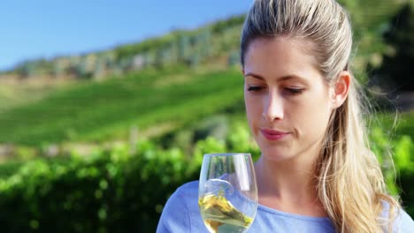 Beautiful-woman-examining-wine-in-vineyard