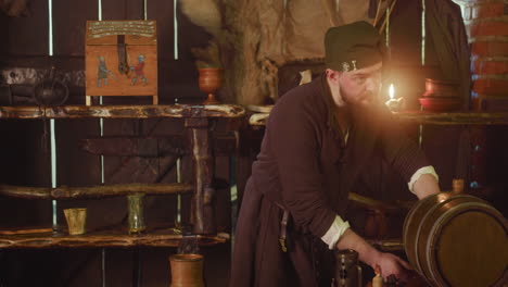 el barman vierte la cerveza del barril y se vuelve hacia el mostrador de la posada. el barman gordo en traje medieval mira con sonrisa servil a los huéspedes en la taberna. mundo de fantasía