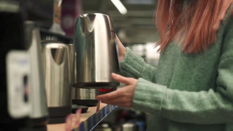 woman in shop of home appliances, choosing electric tea kettle