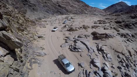 aerial footage of 4x4 convoy of four vehicles travelling thru desert