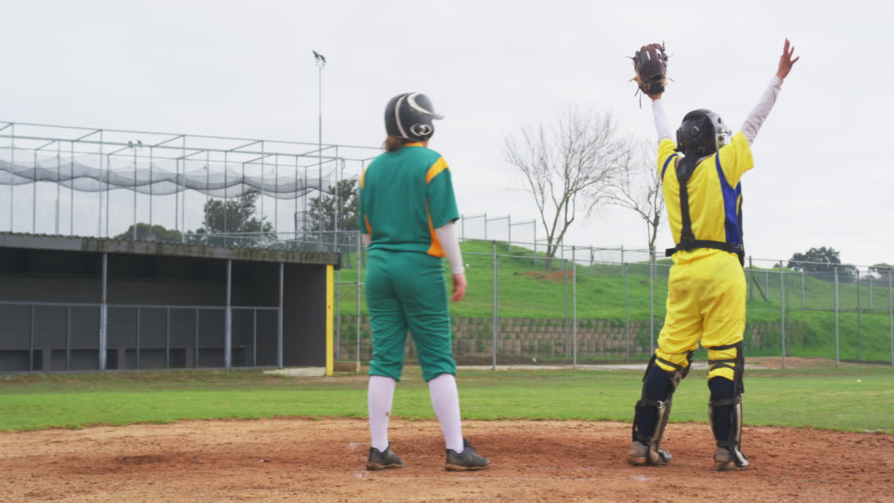 Two white and multiracial female baseball players playing baseball, running through bases on a pitch