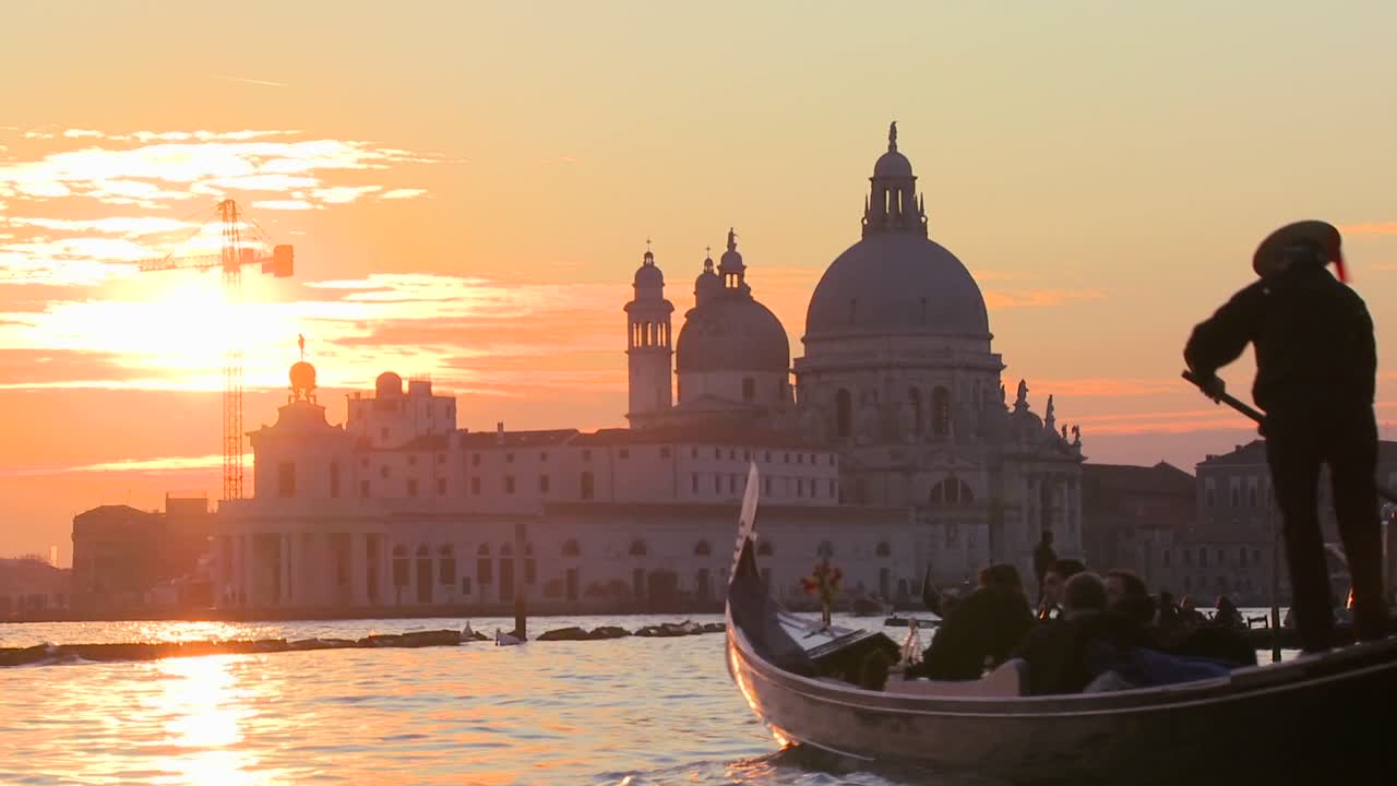 Gondolier wiosłuje gondolą na tle zachodzącego słońca w romantycznej Wenecji we Włoszech 2.
